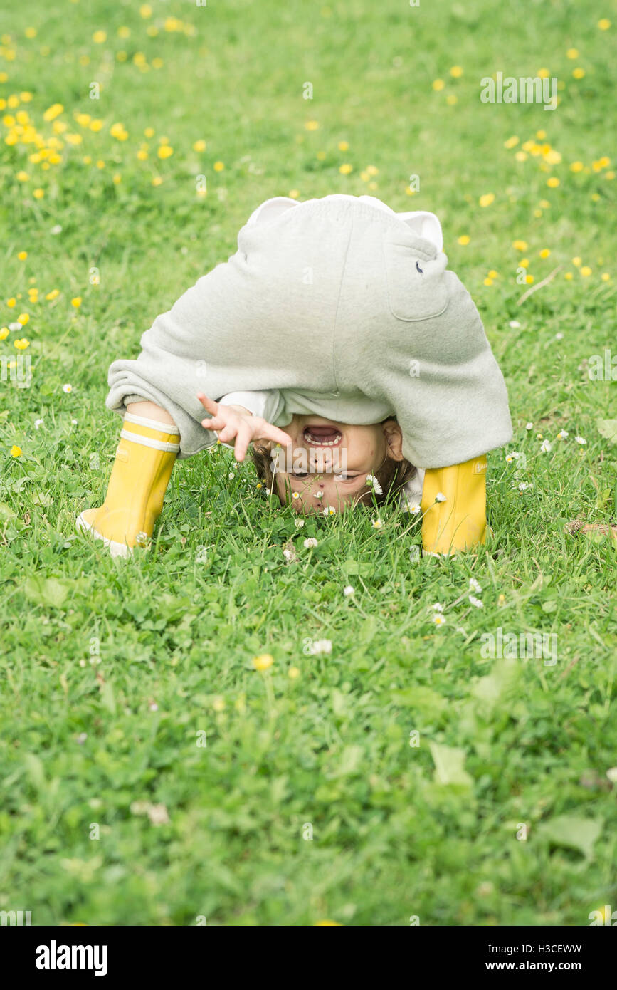 Child bending over, waving through legs Stock Photo