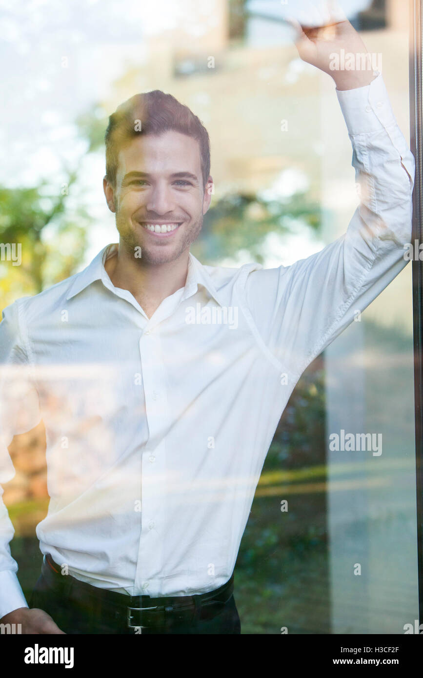 Businessman looking out of window from office Stock Photo