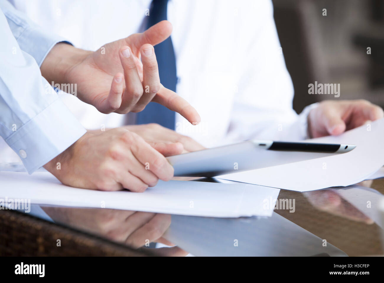 Businessman showing colleague how to use digital tablet Stock Photo