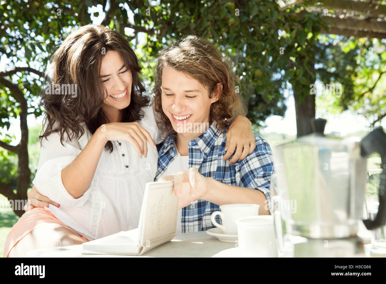 Young couple discussing book at breakfast table outdoors Stock Photo