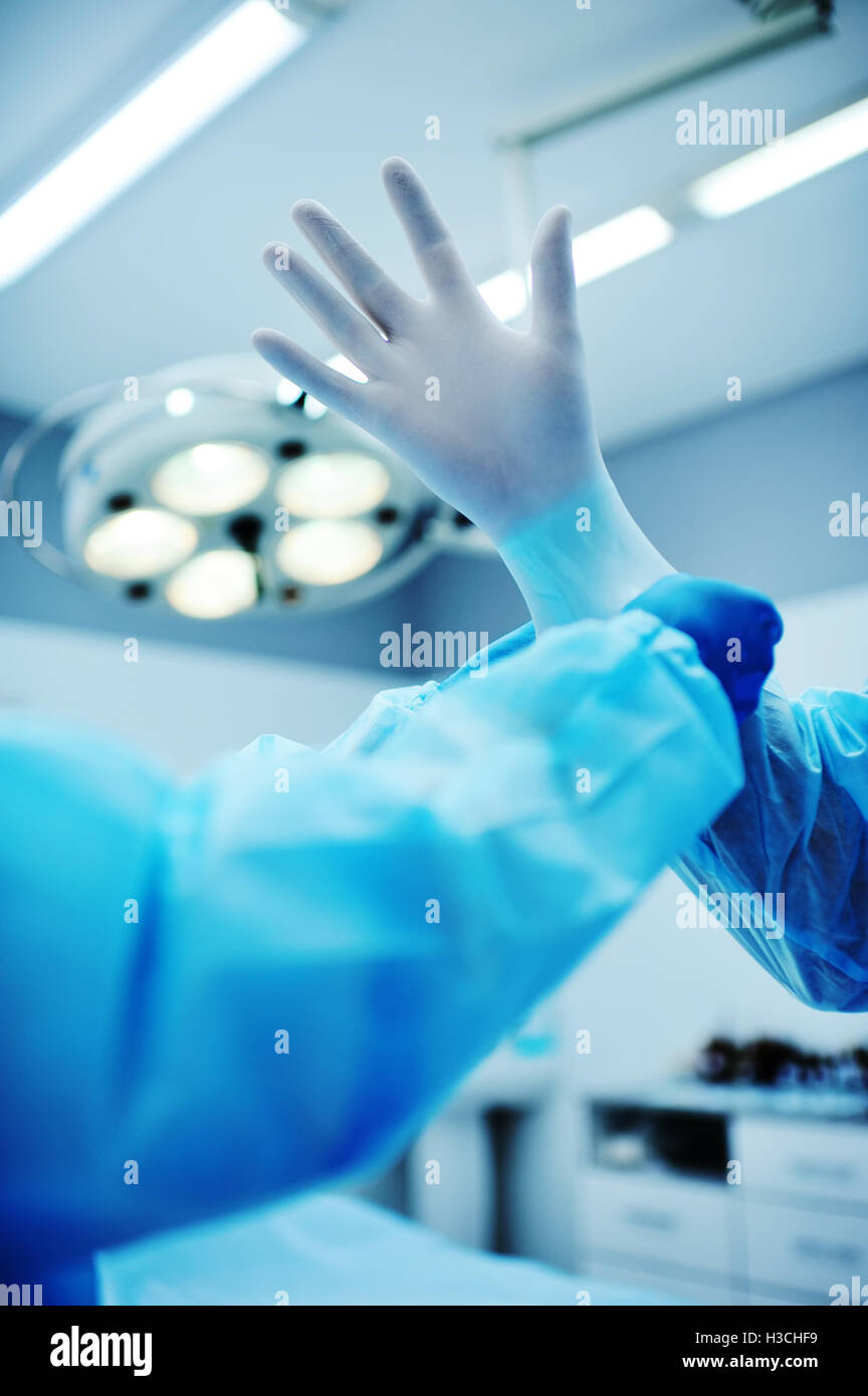 Assistant helps the surgeon put on latex gloves Stock Photo