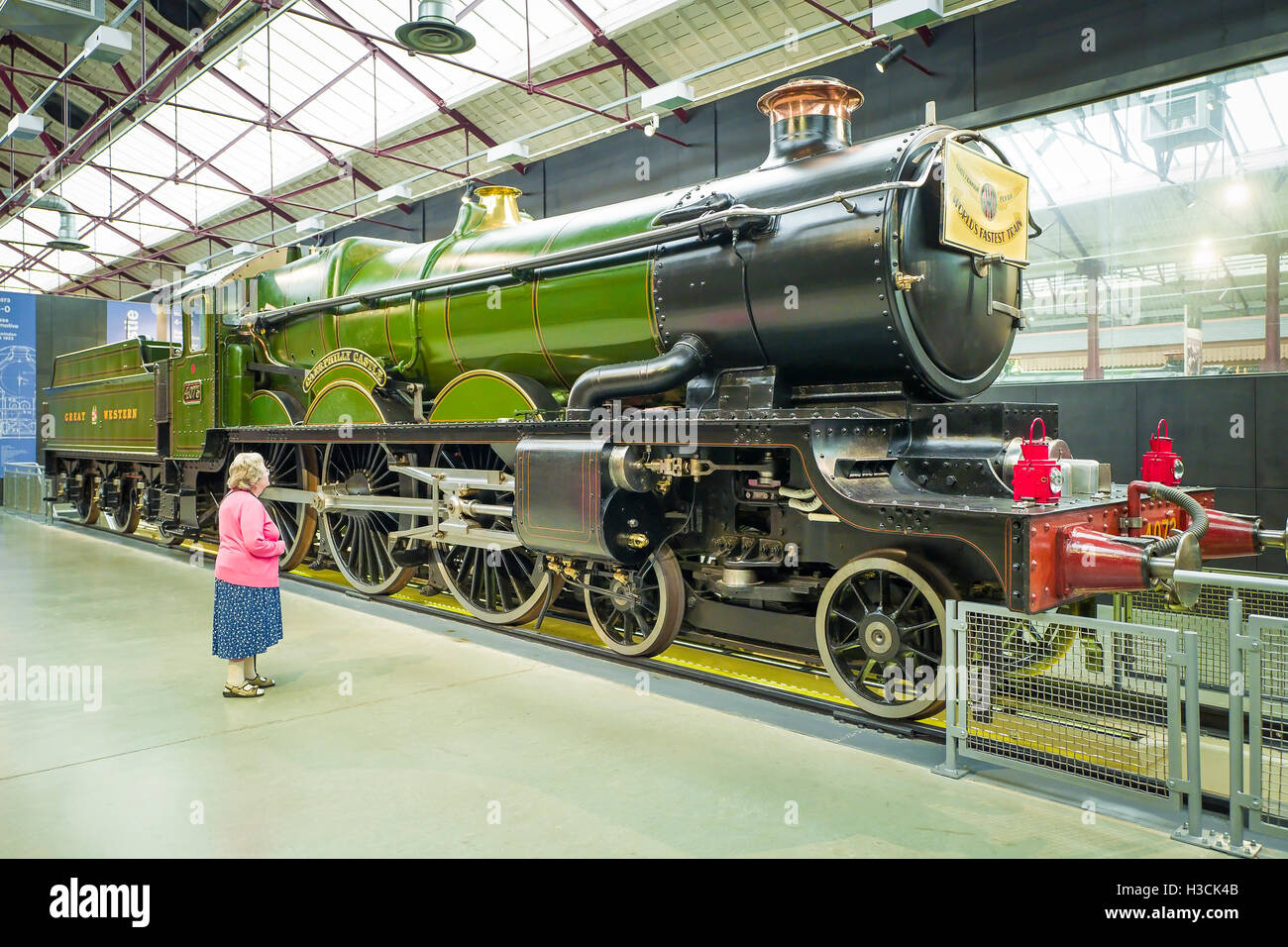 A lady dwarfed by a preserved steam locomotive built in the 1920s and exhibited in the GWR steam museum in Swindon UK Stock Photo