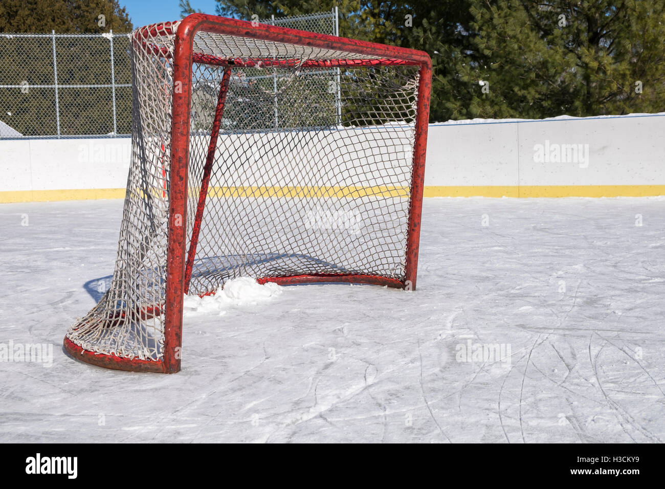 A side view of a red posted ice hockey net on an outdoor hockey rink