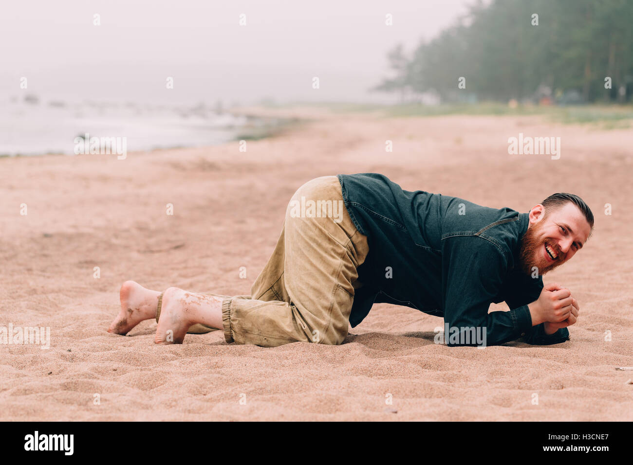 Happy bearded man crawling on all fours  the beach Stock Photo