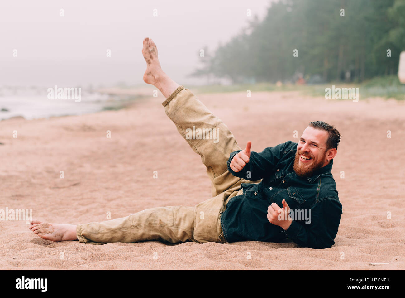 Happy bearded man does morning exercises at the beach Stock Photo