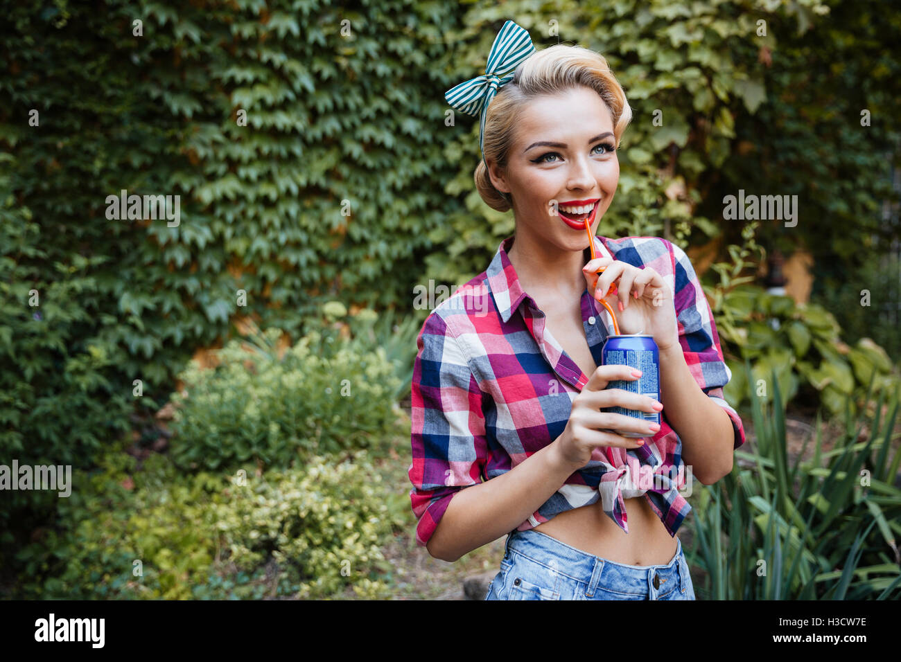 Cheerful lovely pinup girl walking in the park and drinking soda Stock Photo