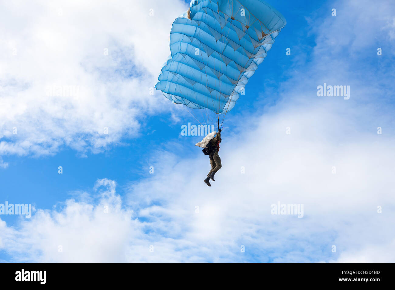 Single military parachute jumper on a blue wing parachute on blue sky