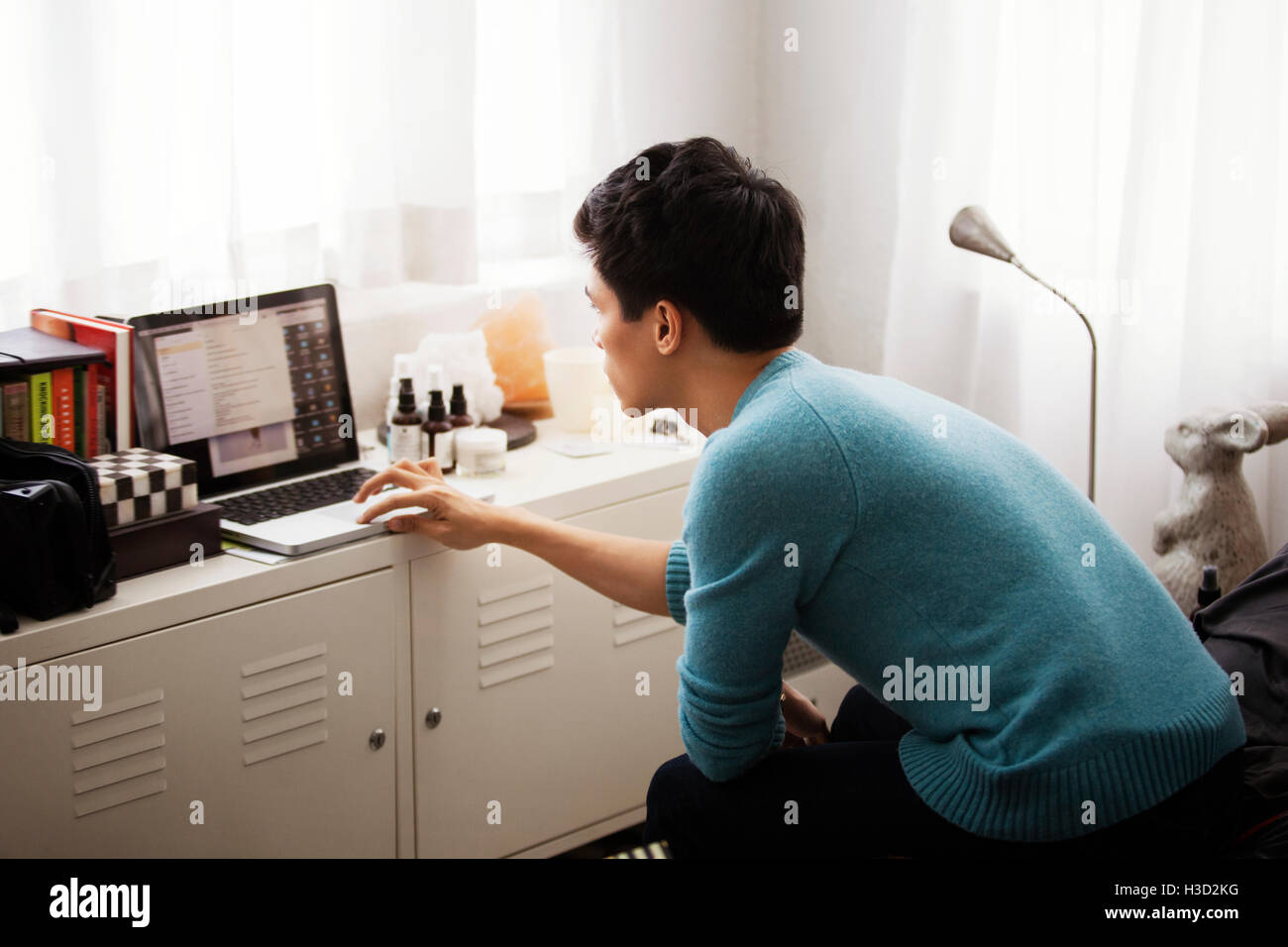 Side view of man using laptop in bedroom Stock Photo - Alamy