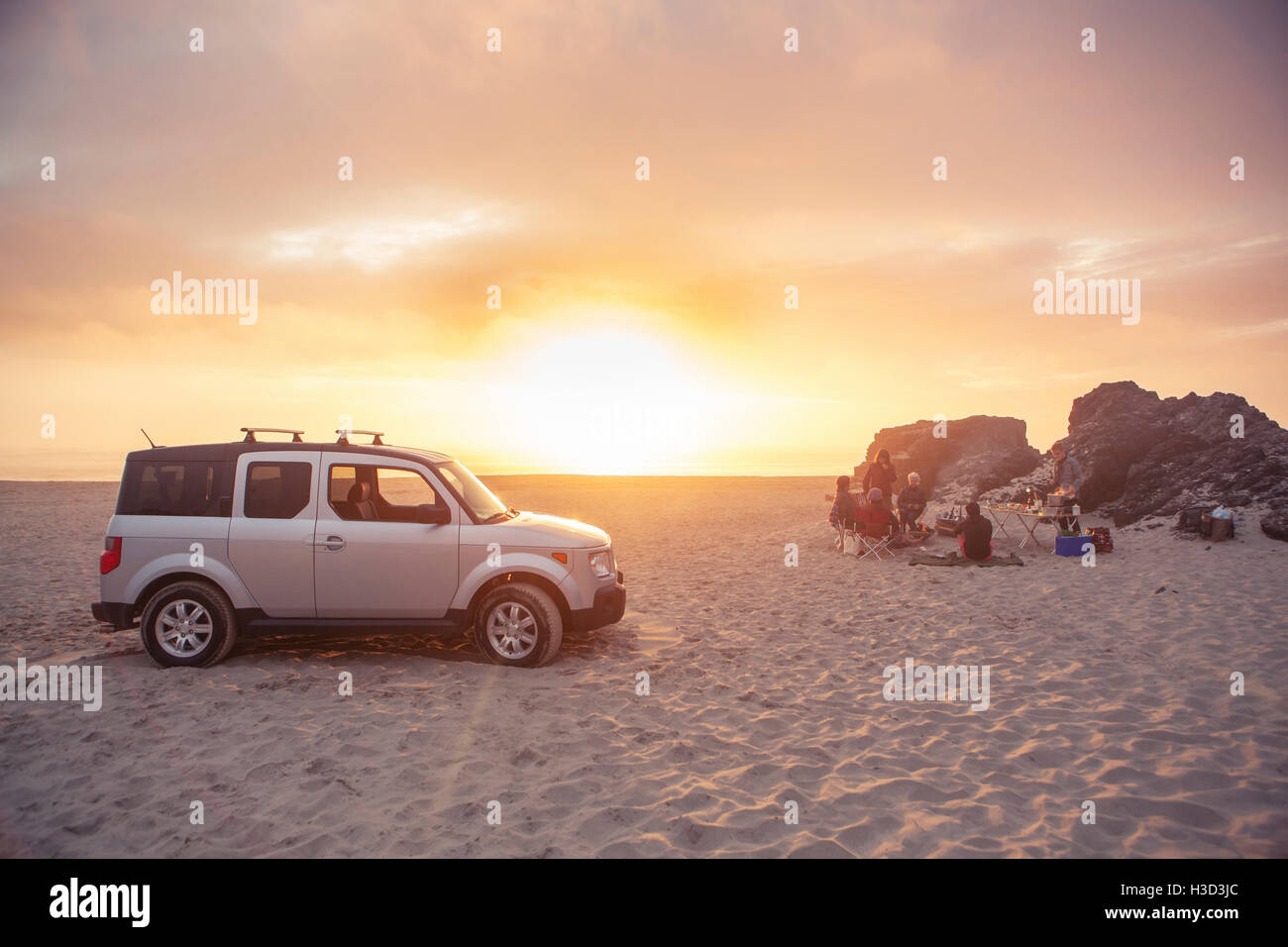 SUV parked on beach while friends camping during sunset Stock Photo