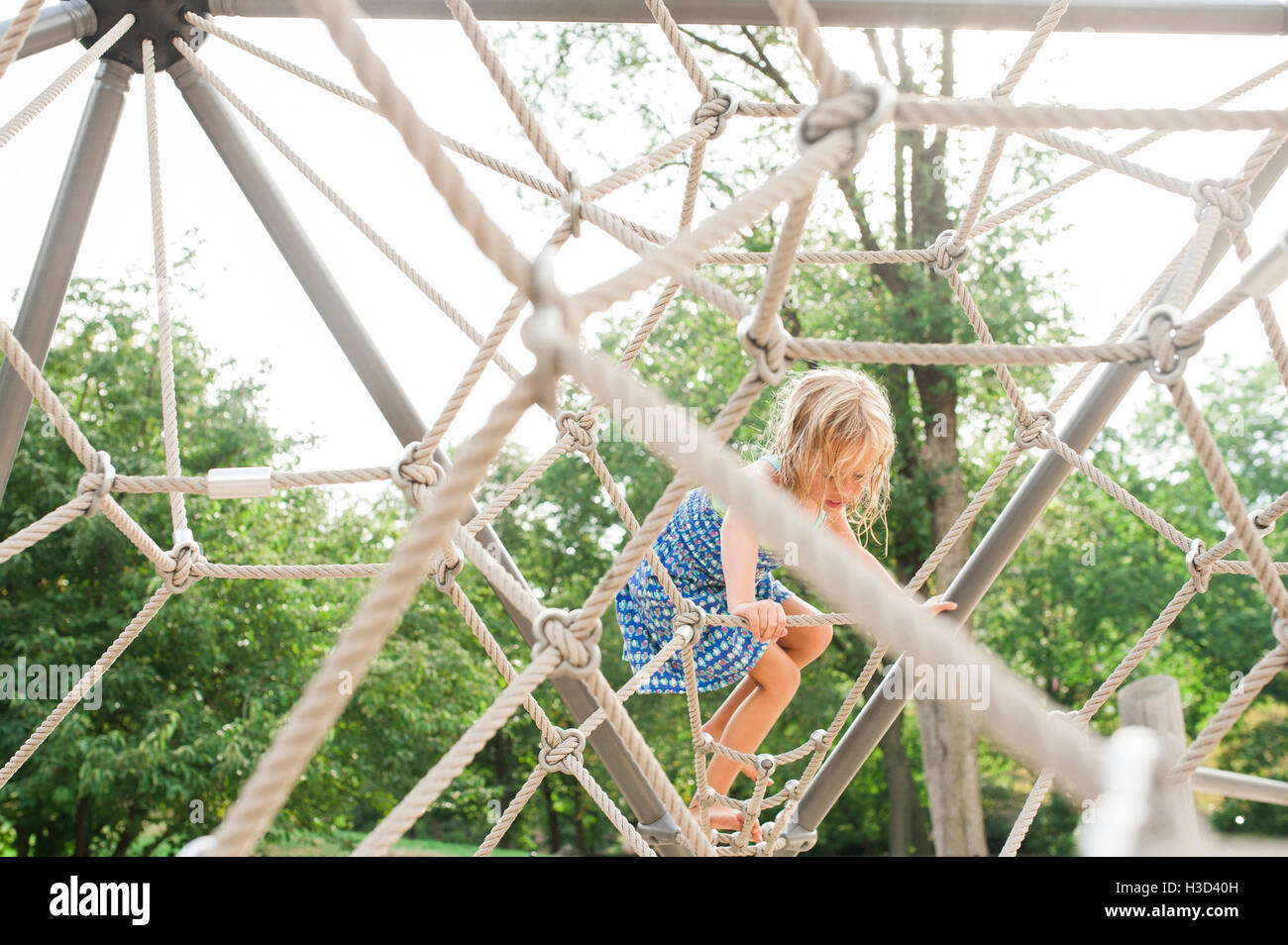 Girl climbing jungle gym in playground Stock Photo