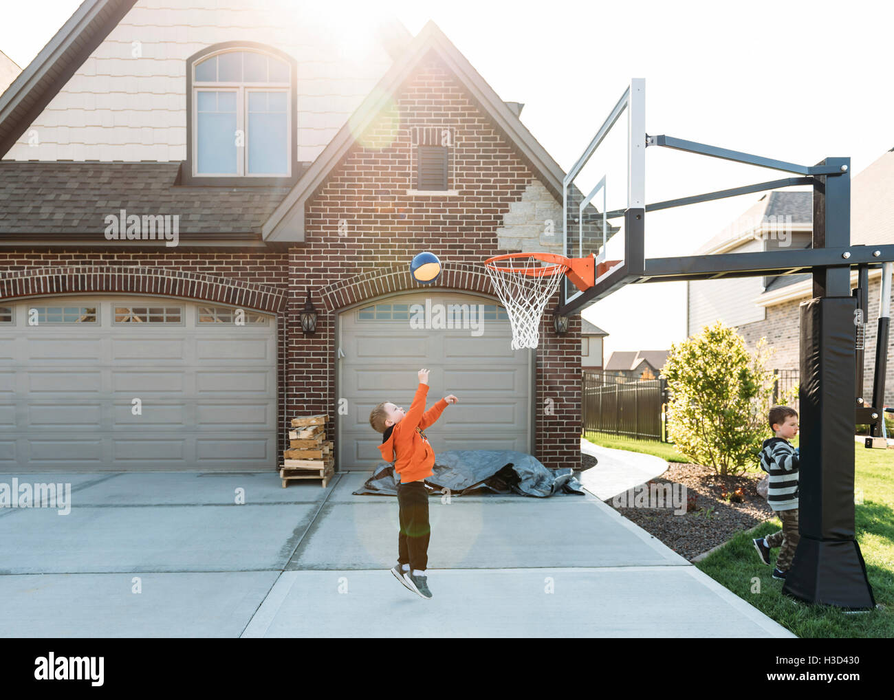 Boy playing basketball with brother at backyard Stock Photo