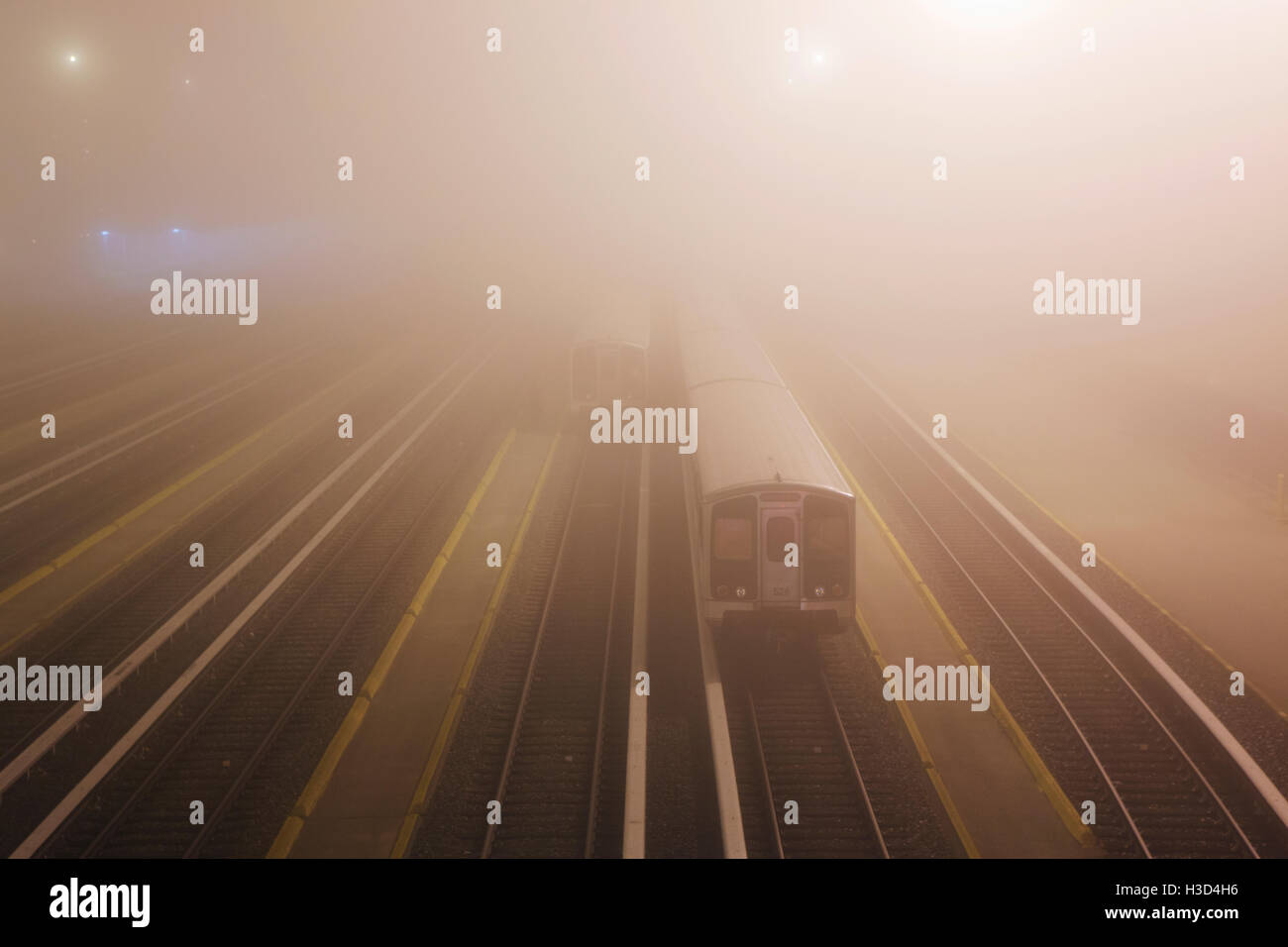 Train on illuminated railroad tracks at dusk in foggy weather Stock Photo