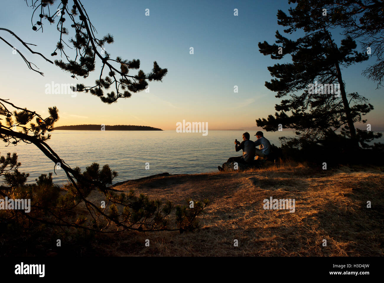Male friends enjoying at Sucia Island against sky during sunset Stock Photo
