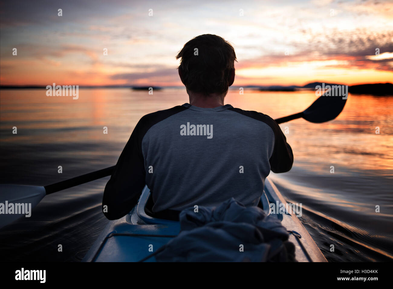 Rear view of man kayaking during sunset Stock Photo