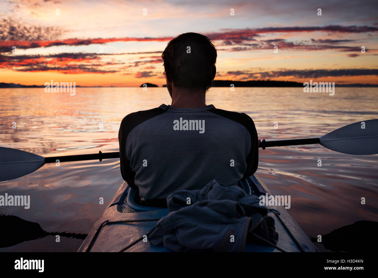 Rear view of man relaxing on kayak during sunset Stock Photo