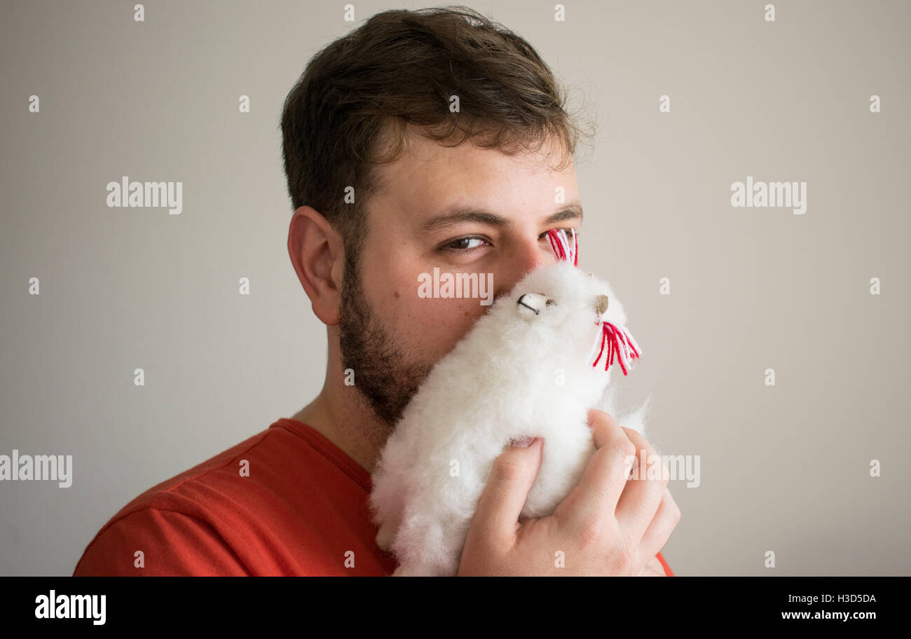 Cute guy holding a stuffed alpaca Stock Photo