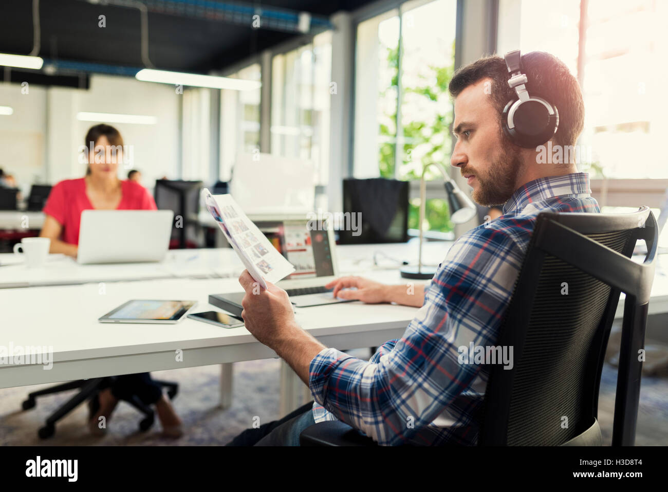 Serious man working on laptop while listening to music in open space ...