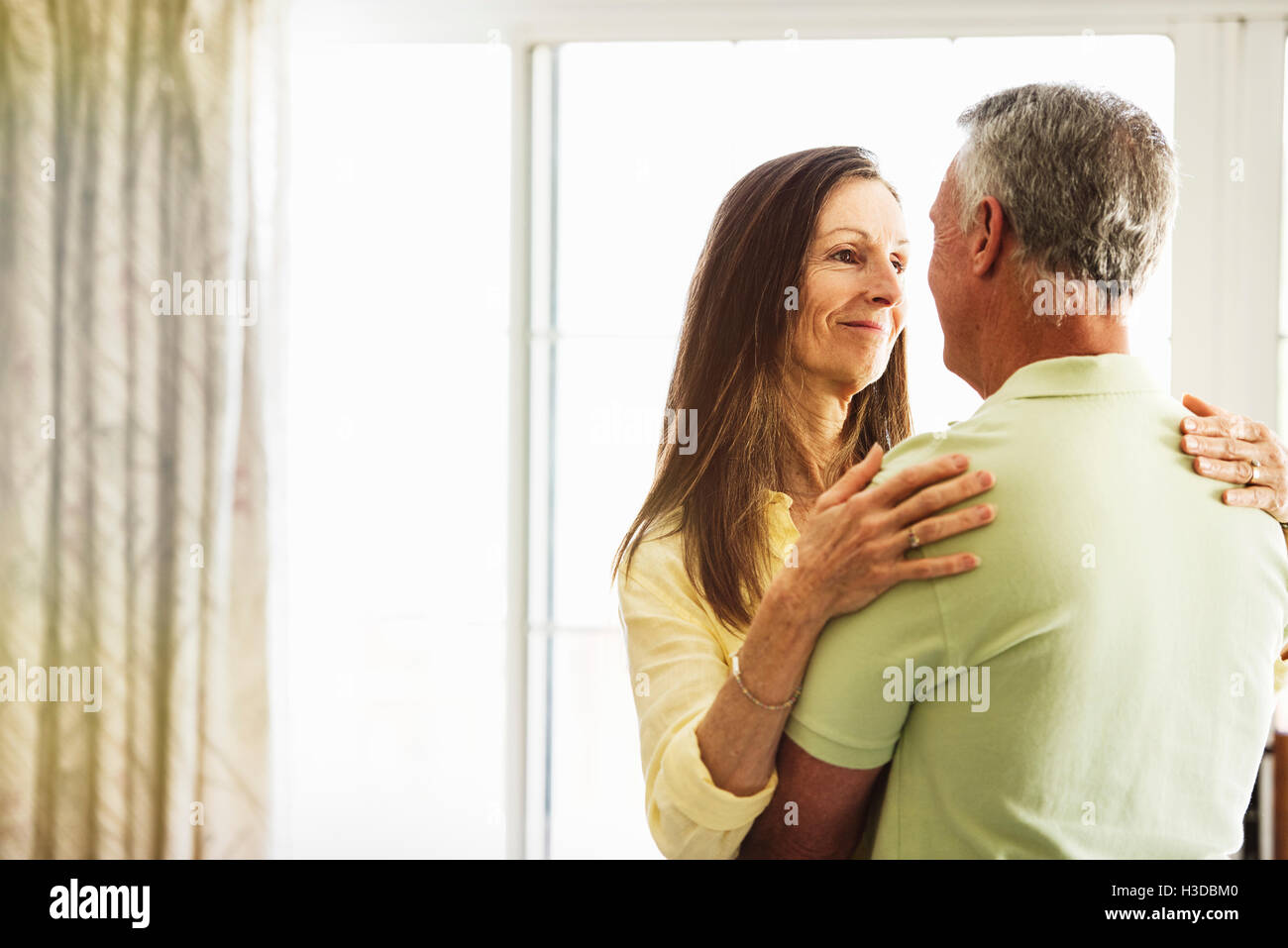 Senior couple standing indoors, embracing. Stock Photo