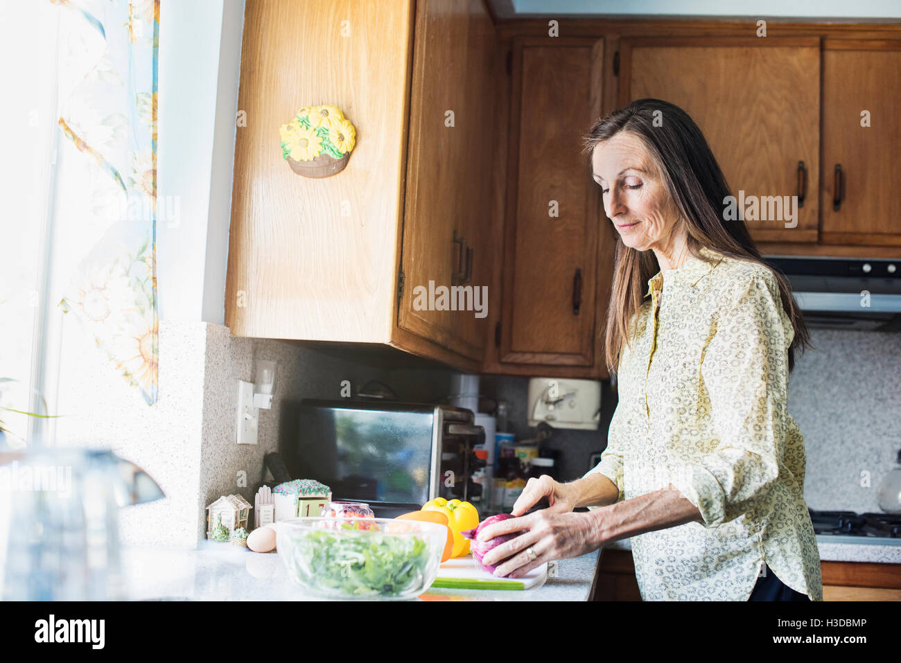 Senior woman standing in a kitchen, preparing food. Stock Photo