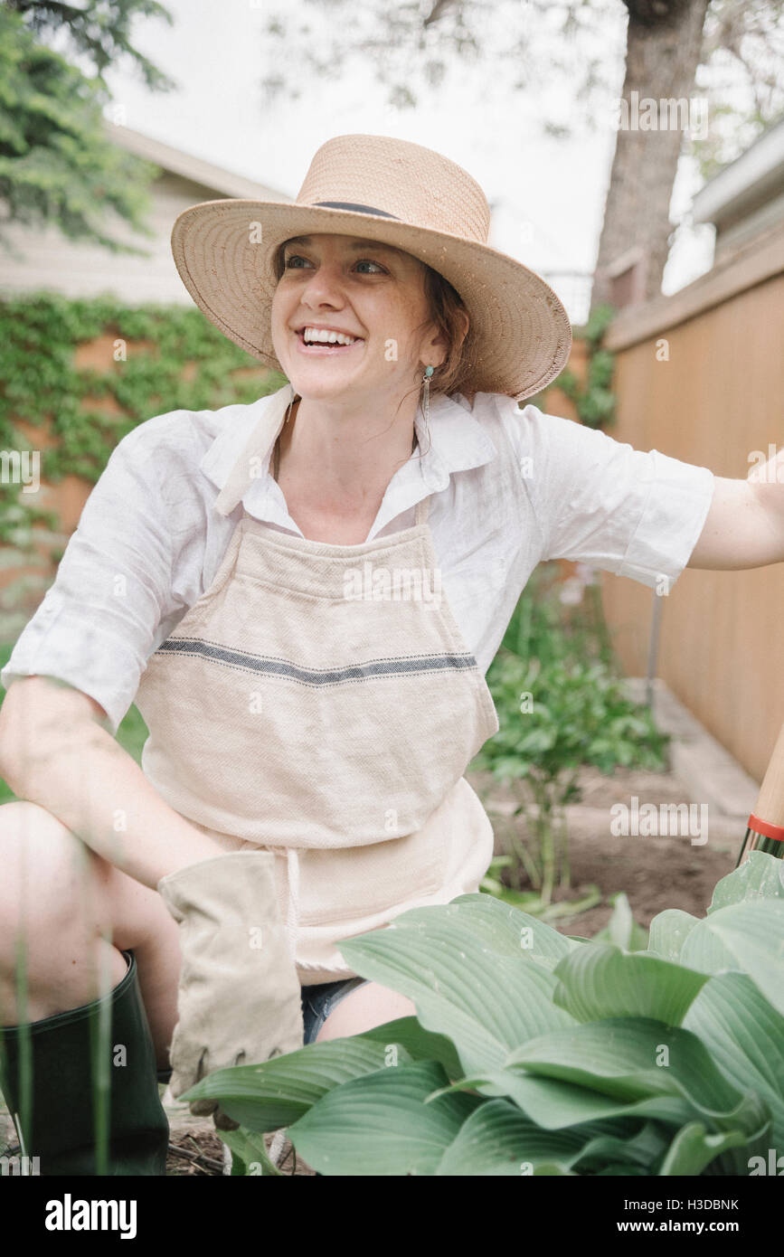 A woman in a wide brimmed straw hat working in a garden, digging. Stock Photo