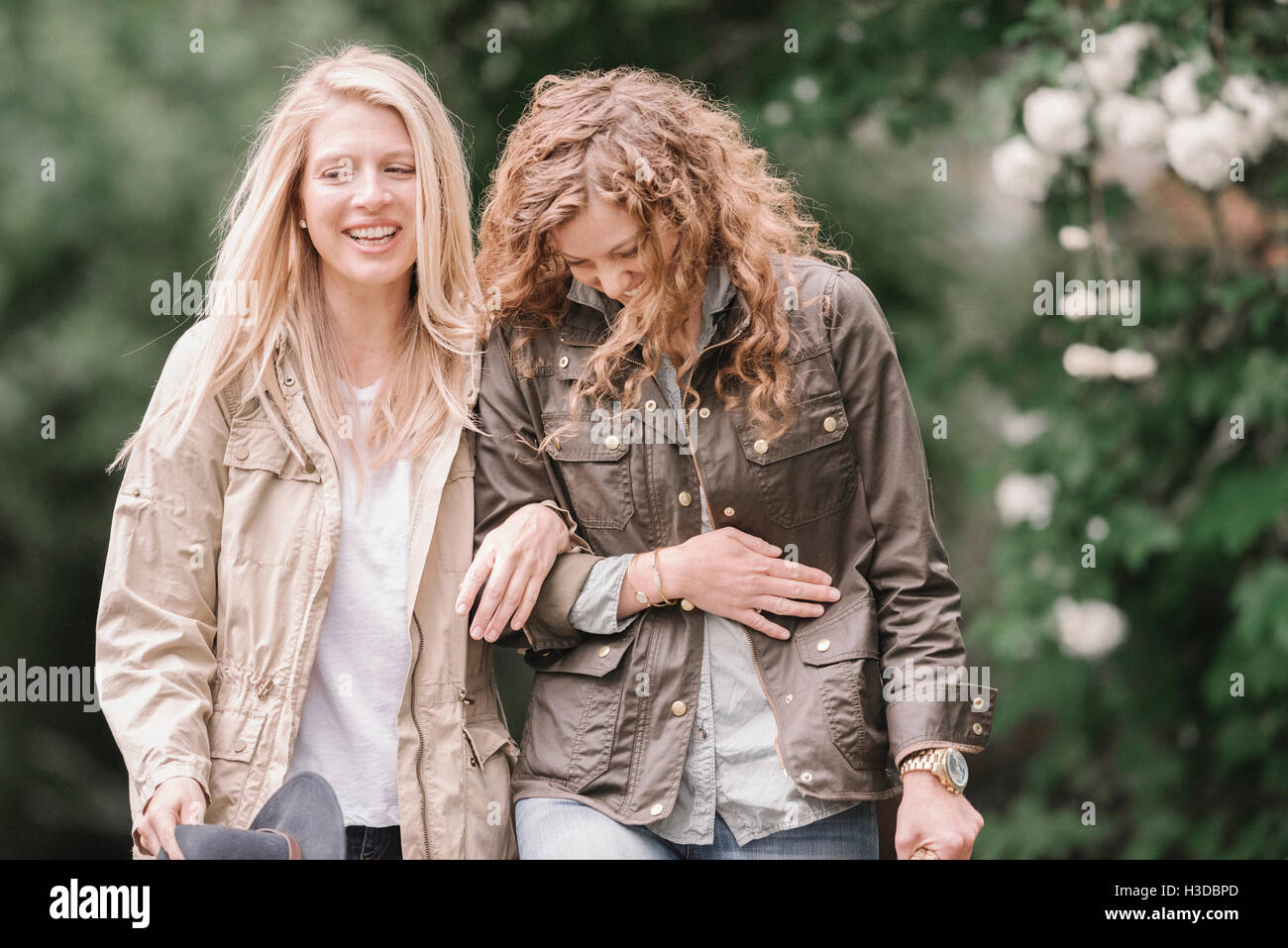 Two women walking arm in arm in the countryside. Stock Photo