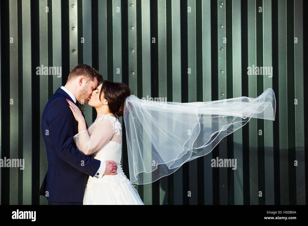 A bride and bridegroom on their wedding day, kissing each other. Stock Photo