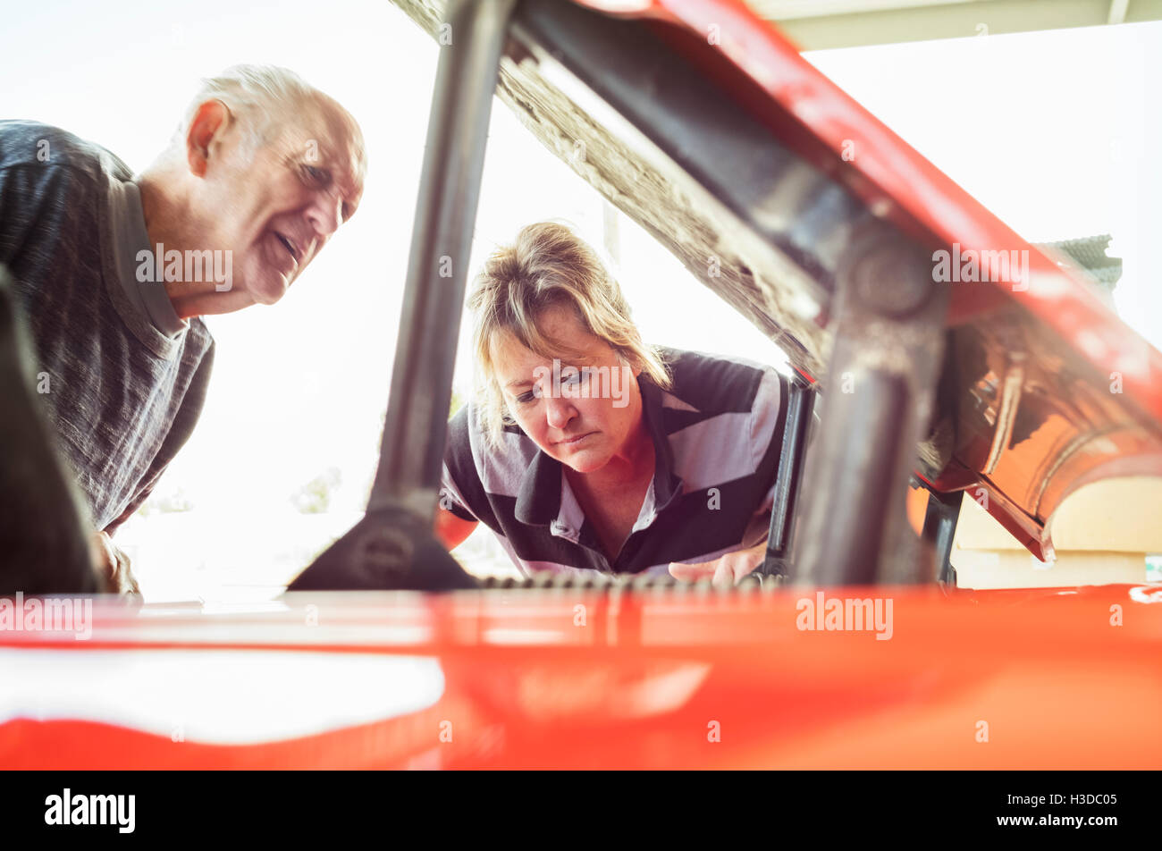 Mature woman and senior man repairing a car, looking under bonnet. Stock Photo