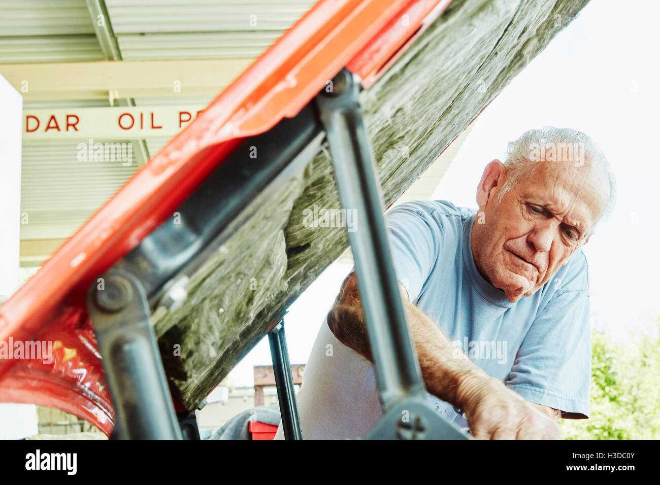 Senior man repairing a car, looking under bonnet. Stock Photo