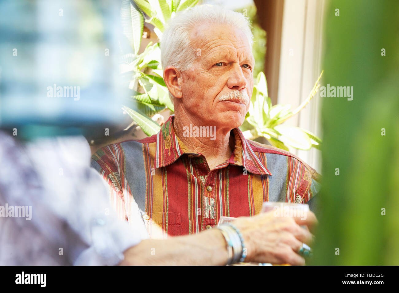 Senior man with moustache sitting outdoors. Stock Photo
