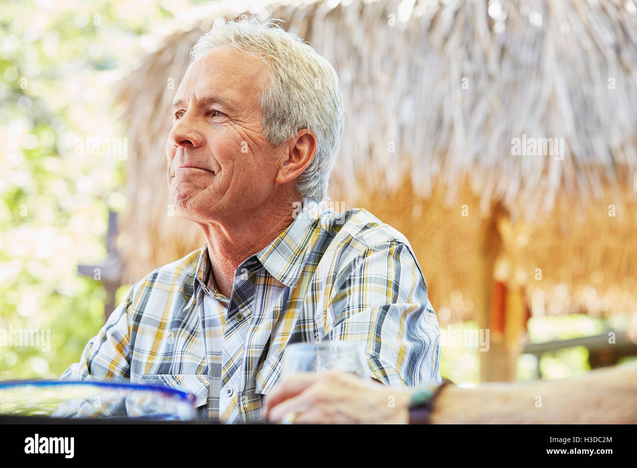 Smiling senior man with grey hair sitting outdoors. Stock Photo