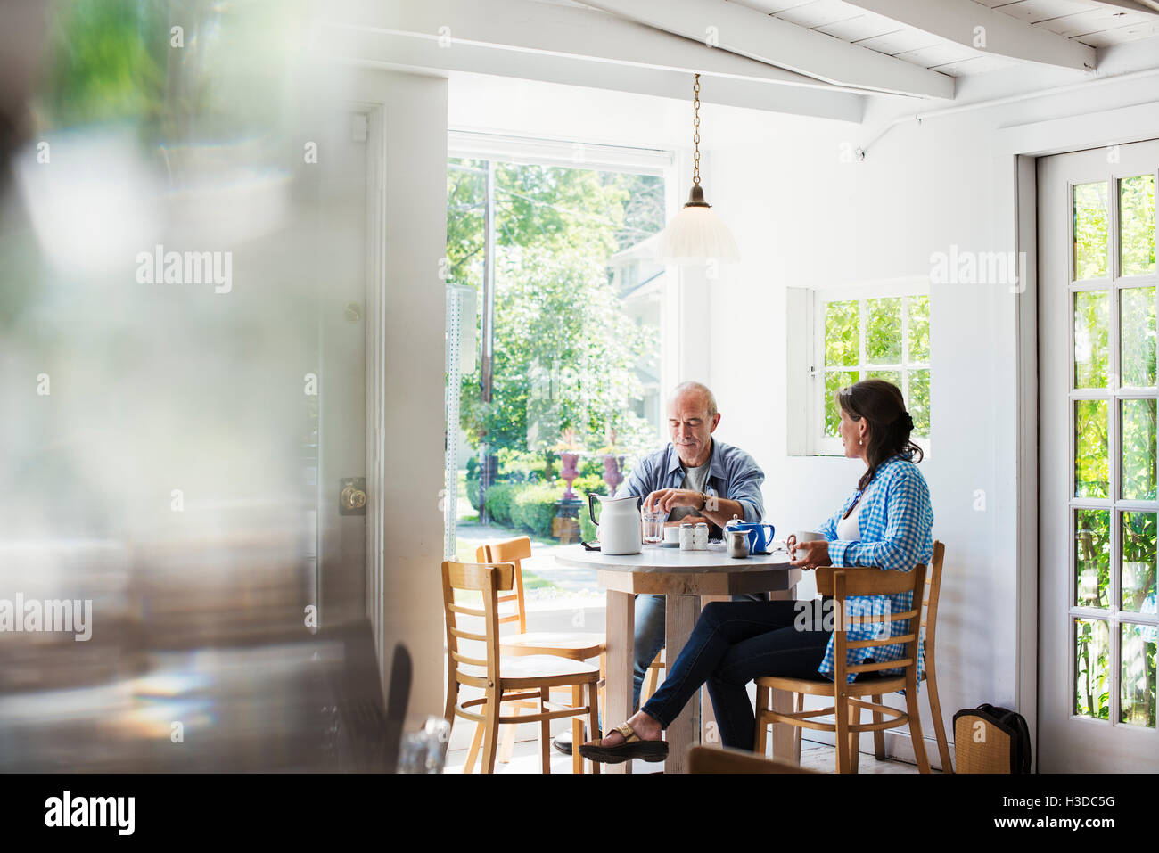 Two People Seated At A Coffee Shop Table By A Window Blurred Foreground Stock Photo Alamy