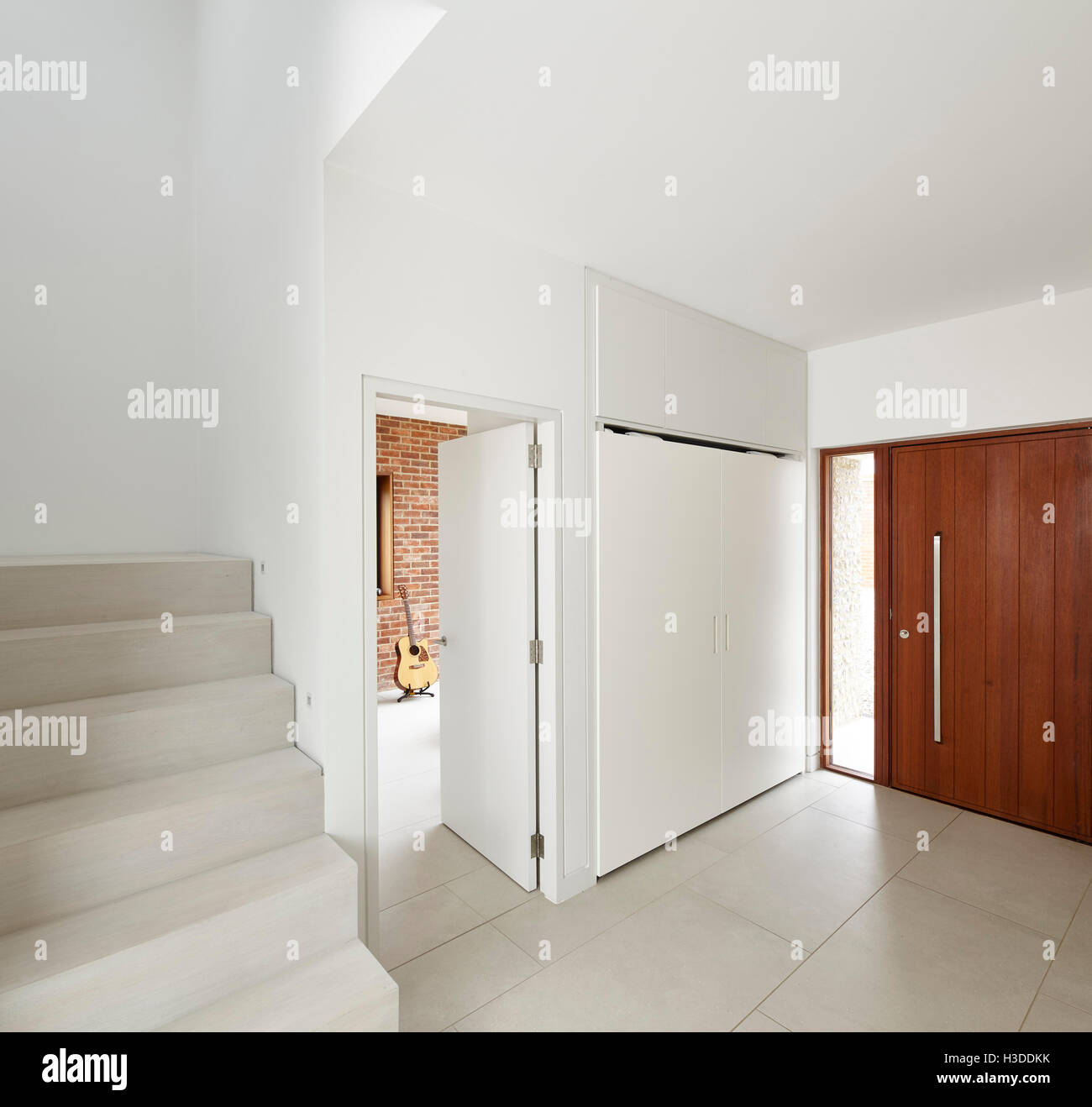 Detail of hallway with oak door and staircase with a guitar in the