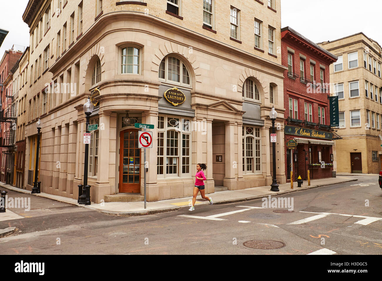 A young asian woman runs along streets of the North End of Boston, MA. Stock Photo