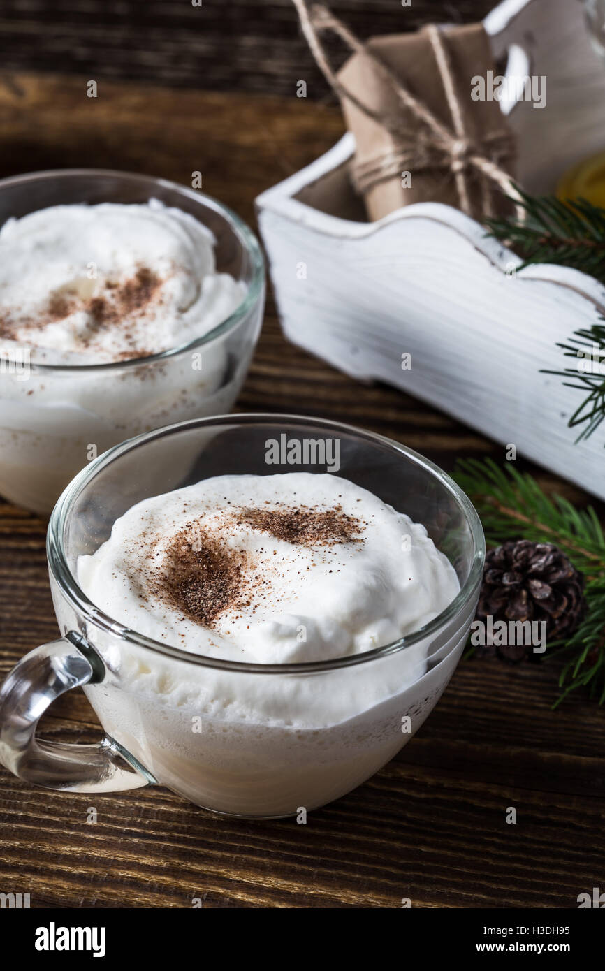 Homemade eggnog with whipped cream in glasses on wooden rustic table ...