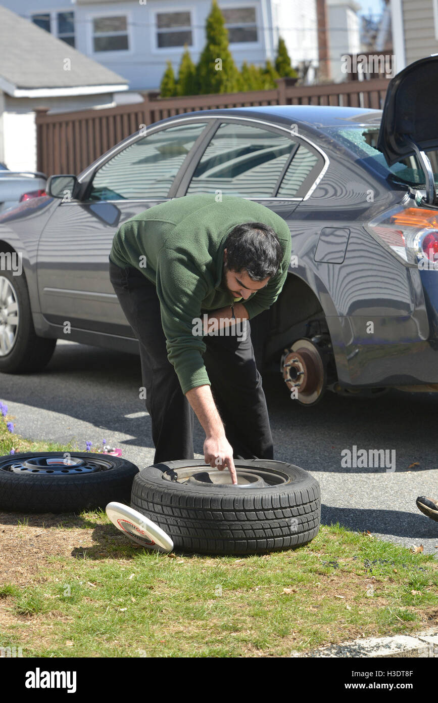 Watertown, Massachusetts, USA. 21st Apr, 2013. Residents of Laurel Street in East Watertown, are changing a tire hit by bullets that damaged automobiles all along the street during the shoot out with the Tsarnaev brothers, accused of being the Boston Marathon bombers. Windows in cars were shot out, bullets penetrated car bodies, bomb fragments are embedded in homes, and many homes are marked with small orange flags indicating entrance holes cause by bullets. © Kenneth Martin/ZUMA Wire/Alamy Live News Stock Photo