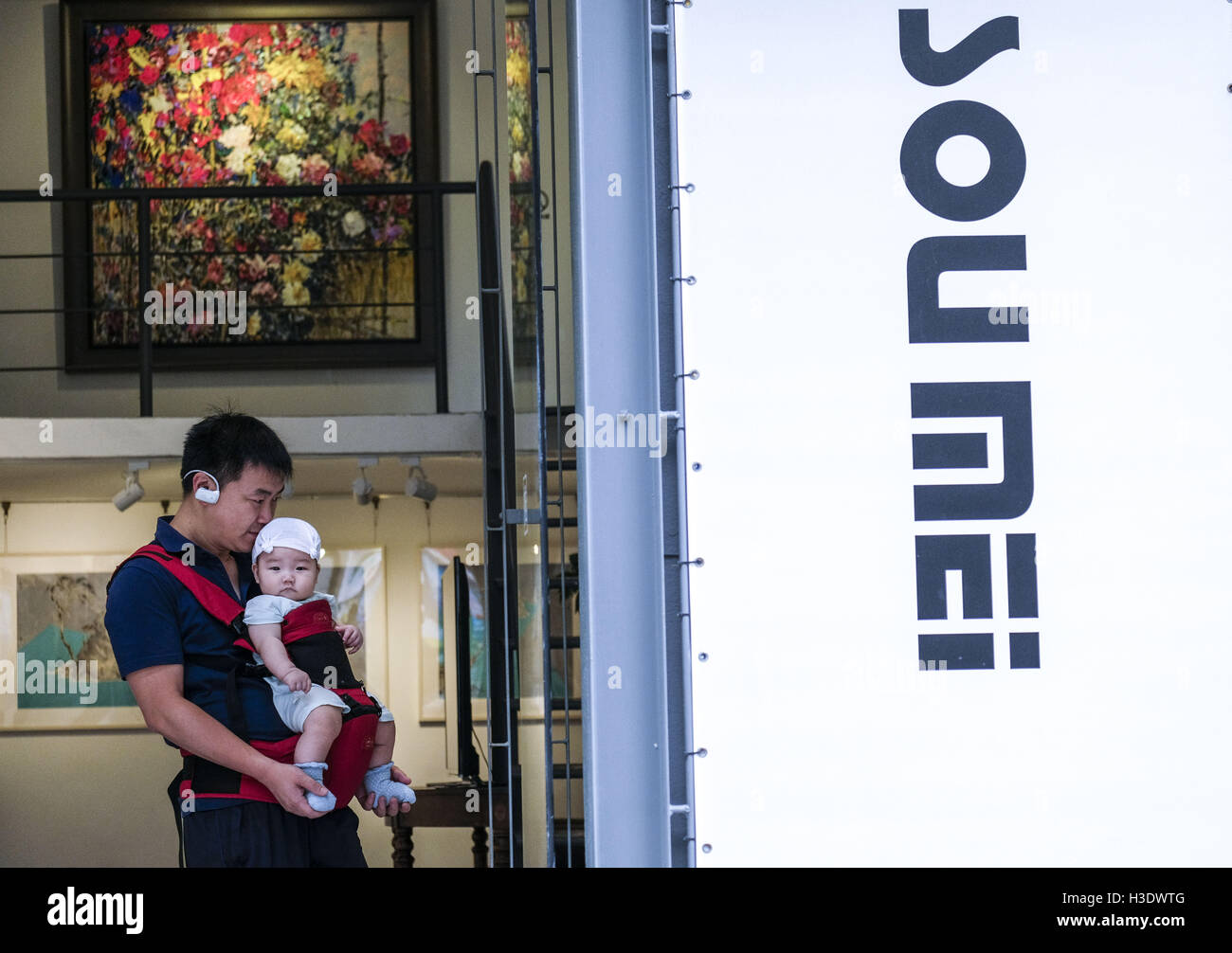 Los Angeles, California, USA. 10th Sep, 2016. A man carries a baby visits a gallery at the M50 Art Colony in Shanghai, China. Shanghai is the most populous city in China and the most populous city proper in the world. It is one of the four direct-controlled municipalities of China, with a population of more than 24 million as of 2014. It is a global financial centre, and a transport hub with the world's busiest container port. Located in the Yangtze River Delta in East China, Shanghai sits on the south edge of the mouth of the Yangtze in the middle portion of the Chinese coast. The munic Stock Photo