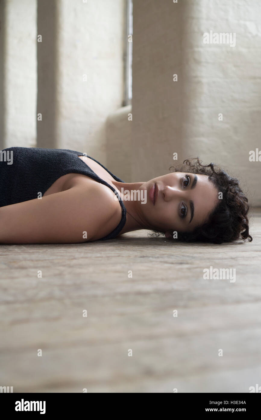 Serious young woman laying down on the floor Stock Photo
