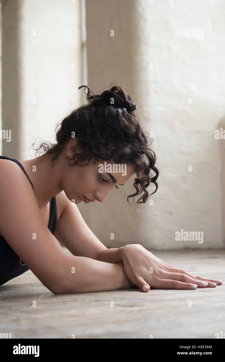 Thoughtful young woman laying down on the floor Stock Photo