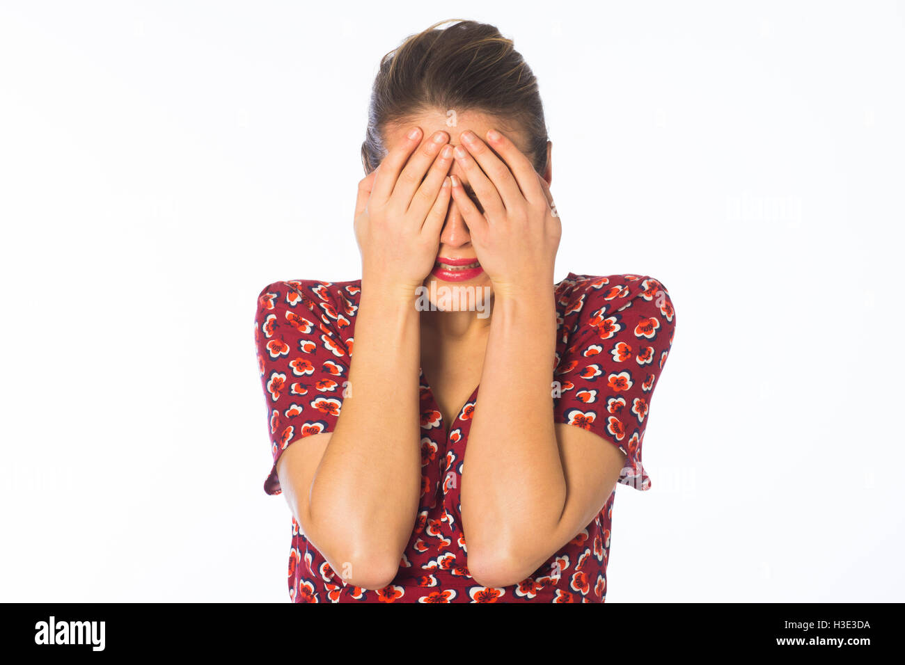 Scared young woman hiding face with hands against a white background Stock Photo