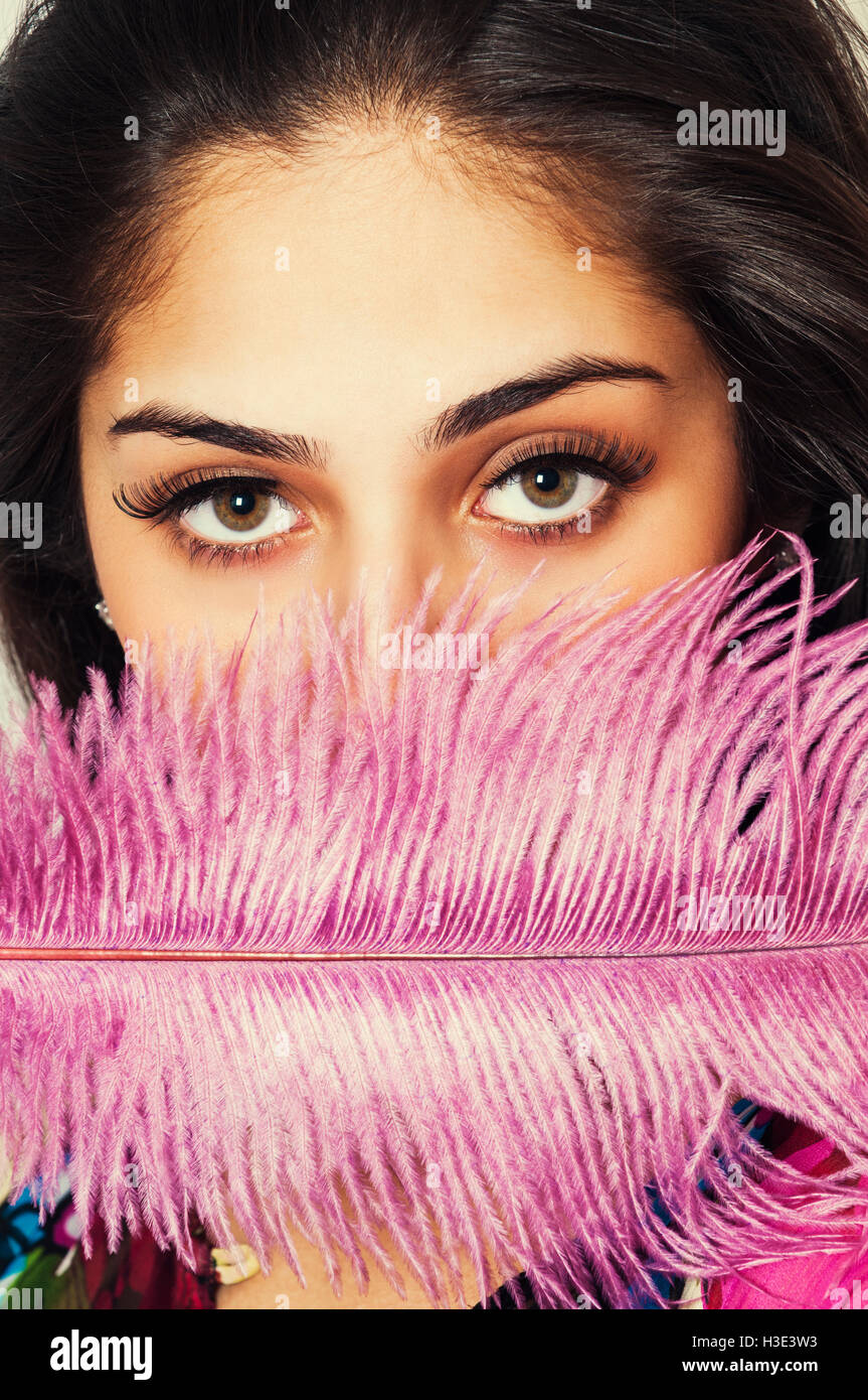 Beautiful young woman hiding face with pink feather Stock Photo