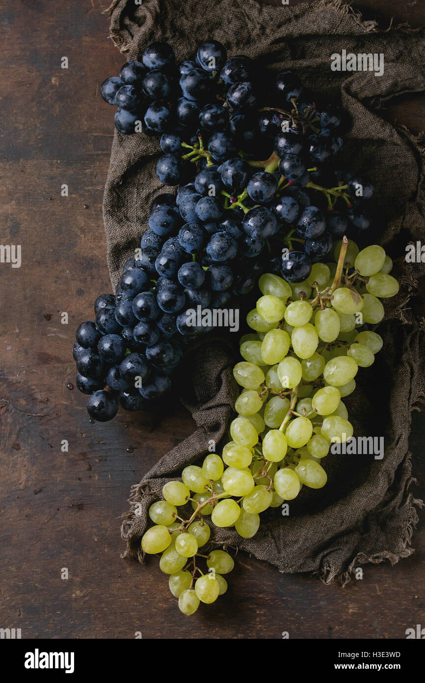Bunches of ripe wet red and white grapes on sackcloth rag over old dark ...