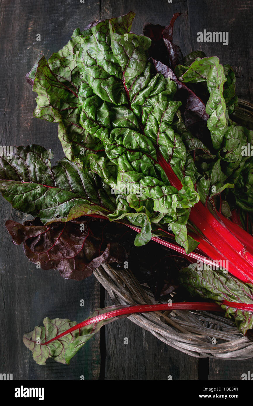 Fresh chard mangold salad leaves in old basket over dark wooden background. Top view with space for text. Healthy eating theme. Stock Photo