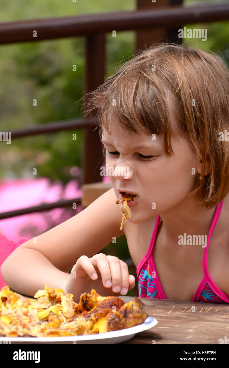 Very hungry girl eats grilled chicken Stock Photo