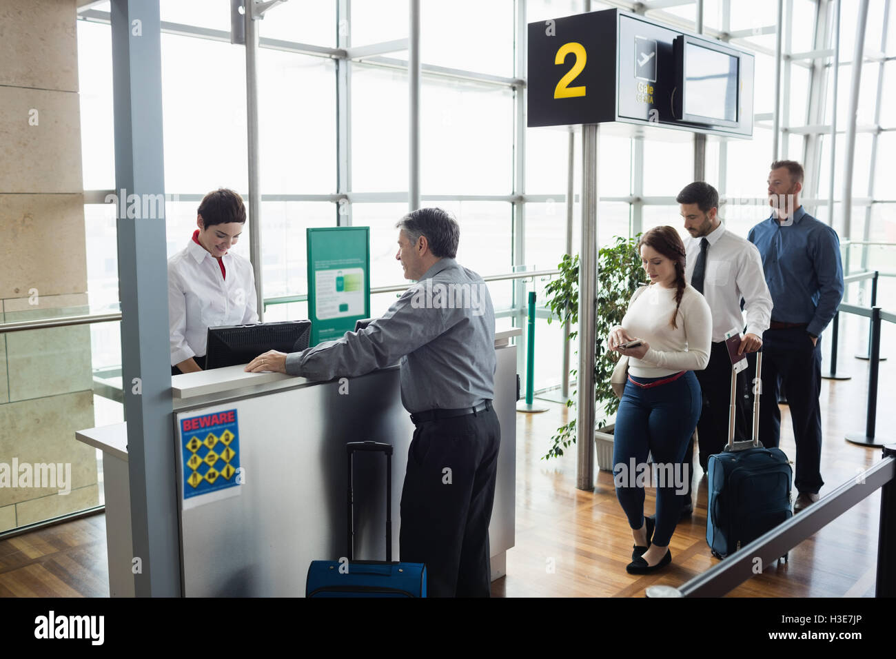 Passengers waiting in queue at check-in counter Stock Photo