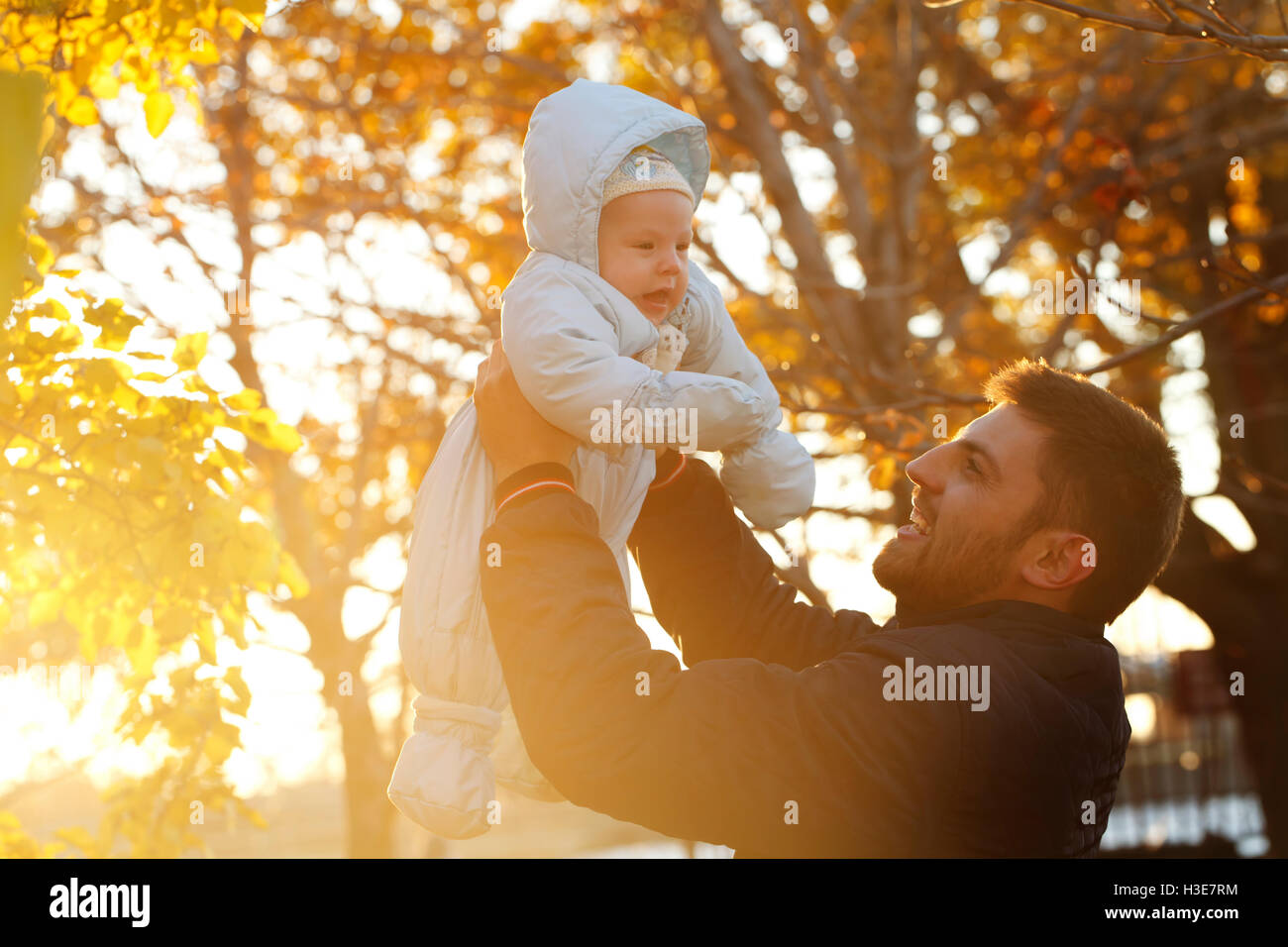 Daddy with the baby for a walk in the park, the father raises the child with the sun Stock Photo