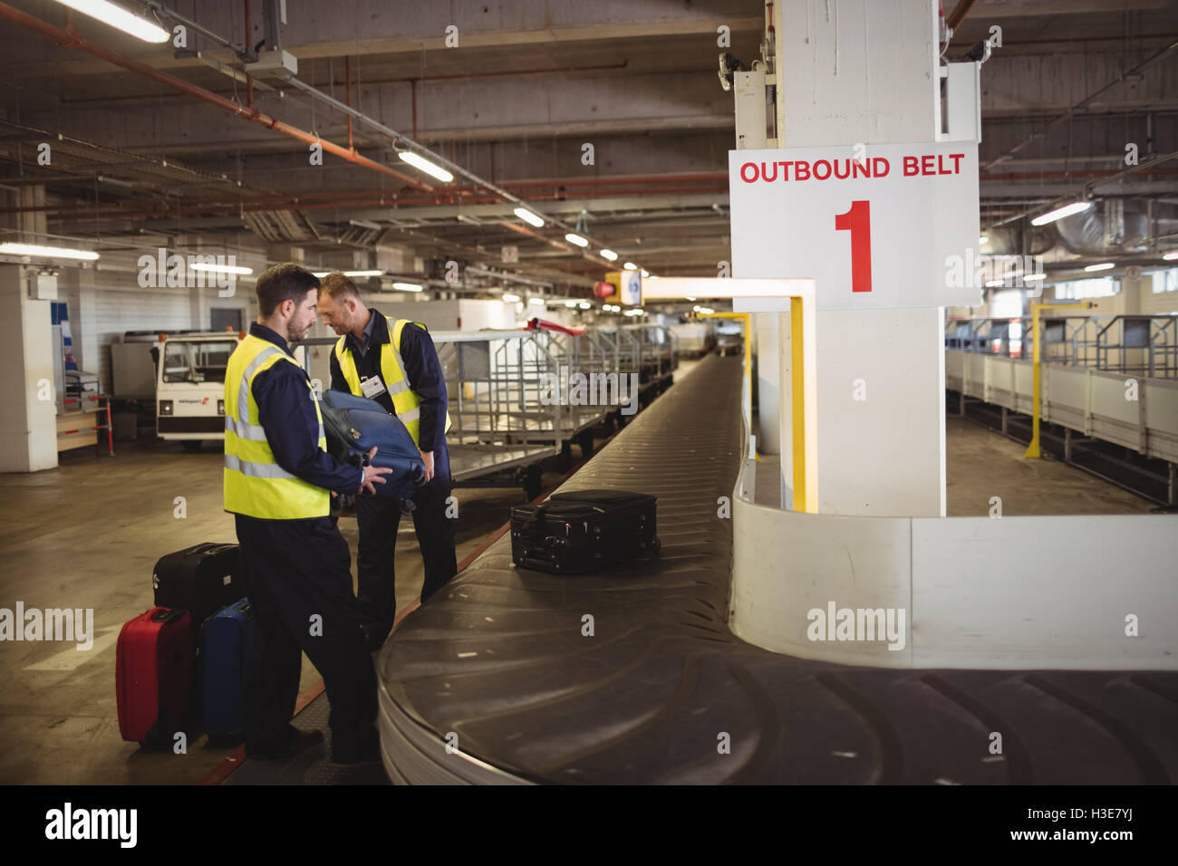 Airport ground crew unloading luggage from baggage carousel Stock Photo
