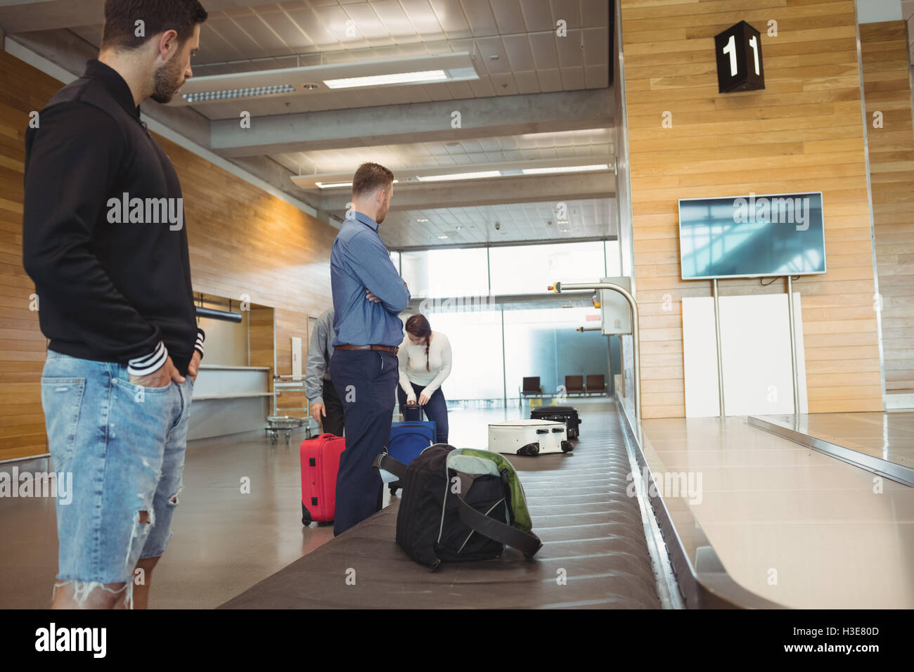 People waiting for luggage in baggage claim area Stock Photo