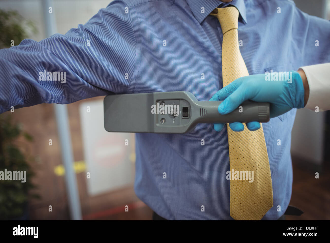 Airport security officer using a hand held metal detector to check a