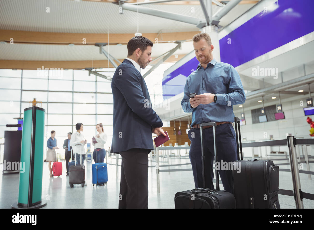 Business people waiting at check-in counter with luggage Stock Photo