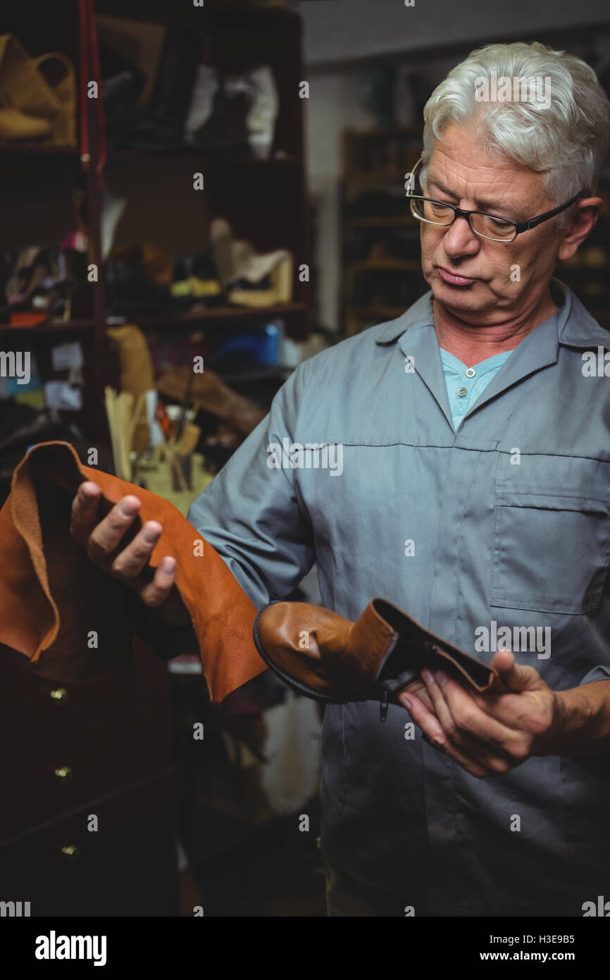 Shoemaker examining a boot and piece of material Stock Photo - Alamy